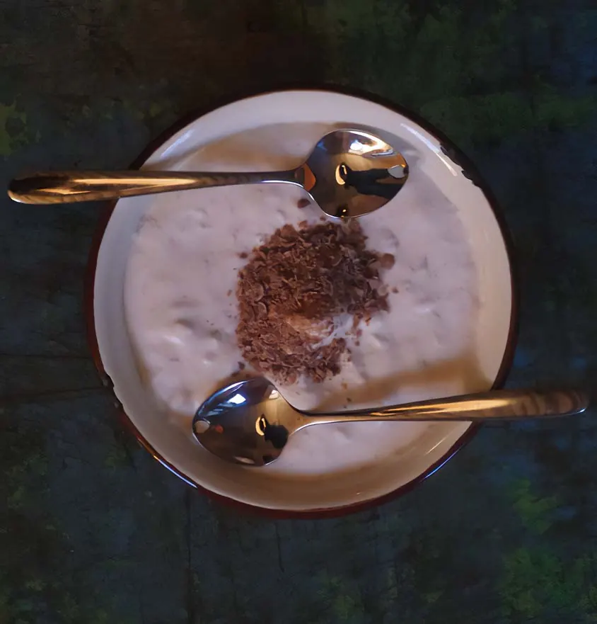 Bananencreme auf einem weißen Teller mit blauem Rand, zwei Löffel