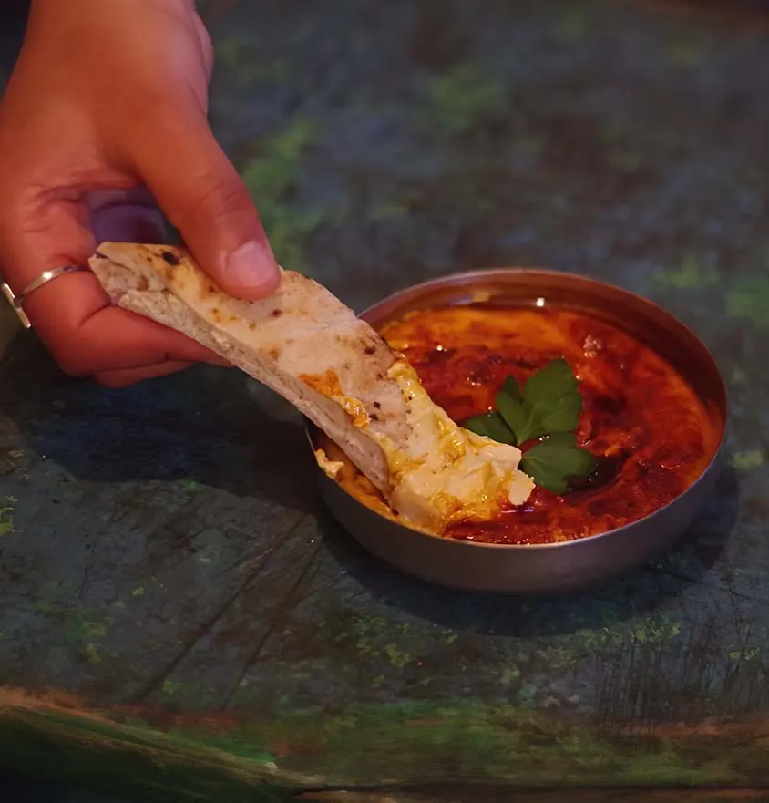 Ein Stück Fladenbrot wird in Hummus mit Berbere getunkt